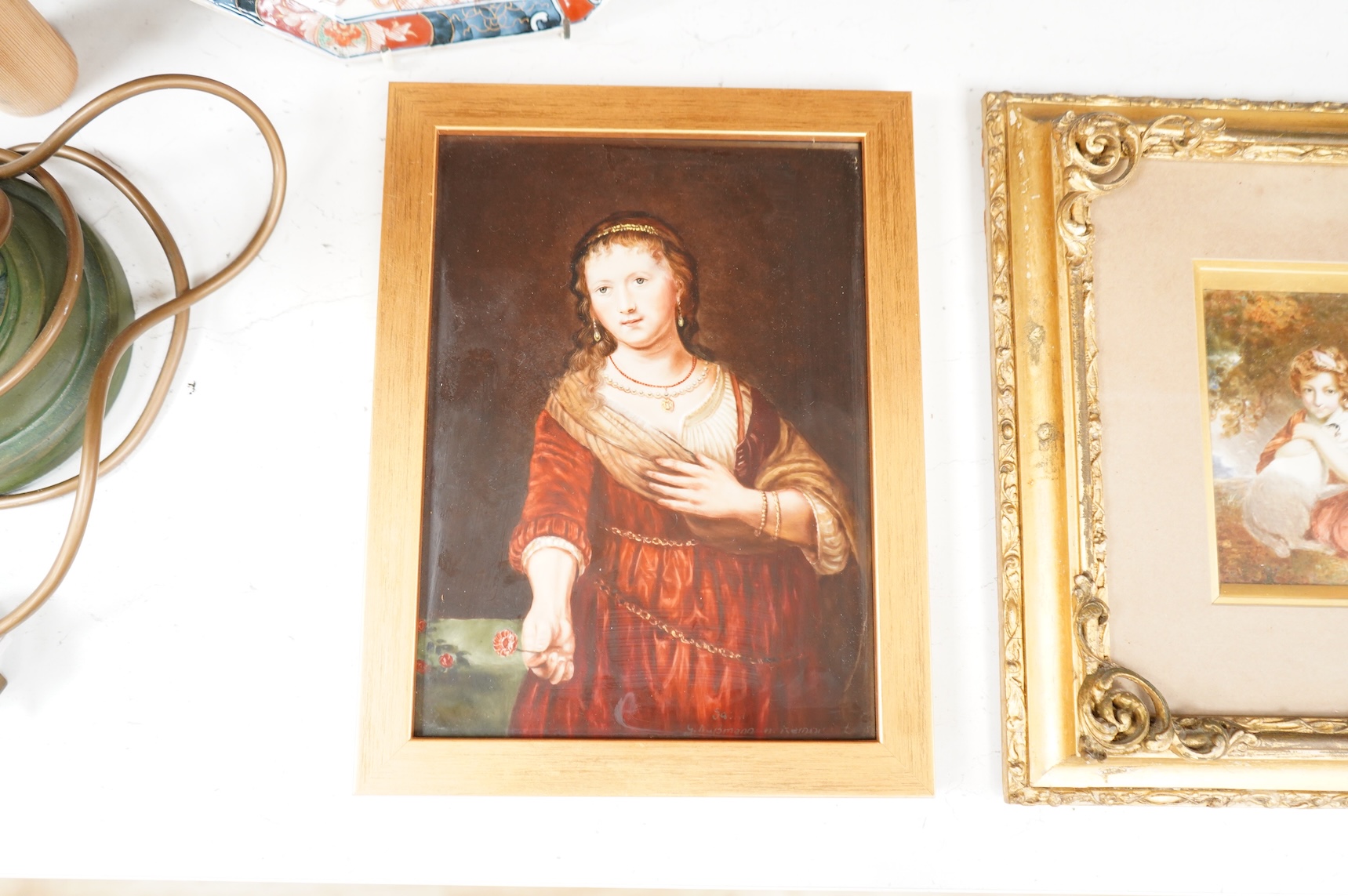 A Continental painted porcelain plaque of Saskia van Uylenburgh, after Rembrandt, together with another plaque of a young girl and her dog, after John Russell (2), Largest 17cm wide x 24cm high.